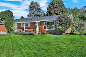 Single story home featuring a front yard, brick siding, a garage, and roof with shingles