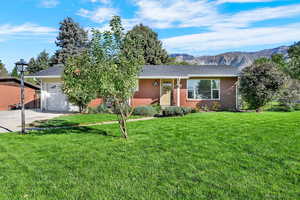 View of front facade featuring a front lawn, a mountain view, an attached garage, and concrete driveway