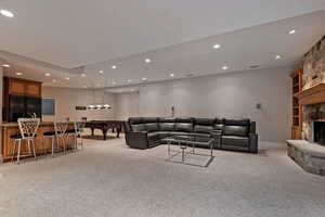 Living area with billiards, recessed lighting, light carpet, a stone fireplace, and bar