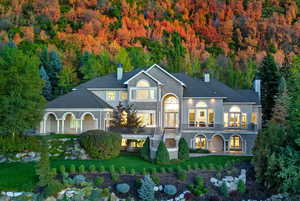Back of property featuring a chimney, a yard, and a wooded view