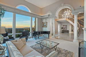 Living area featuring a chandelier, ornate columns, a high ceiling, and stairs