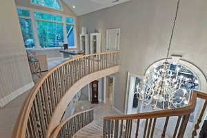 Staircase with a chandelier and high vaulted ceiling