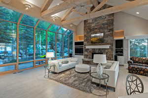 Living room with a sunroom, high vaulted ceiling, a fireplace, beam ceiling, and recessed lighting