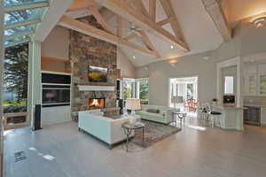 Living area featuring high vaulted ceiling, a fireplace, light wood finished floors, beamed ceiling, and beverage cooler