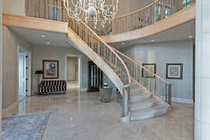 Stairs with recessed lighting, a chandelier, a towering ceiling, and marble tiled floors