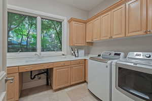 Laundry room with separate washer and dryer, light tile patterned flooring, and cabinet space
