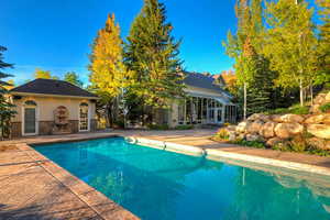 Outdoor pool with a patio area, an exterior structure, and an outdoor structure