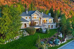 Back of property featuring a chimney, a forest view, and a yard