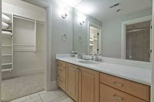Bathroom with vanity, light tile patterned floors, light colored carpet, and a closet