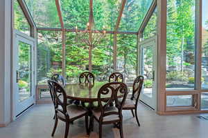Sunroom / solarium featuring healthy amount of natural light, wood finished floors, and a chandelier