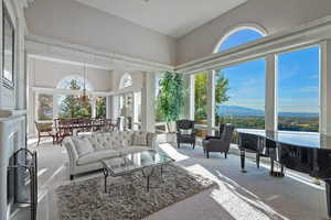Sunroom / solarium with carpet flooring, a chandelier, and a high ceiling