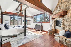 Bedroom with beam ceiling, hardwood / wood-style flooring, a fireplace, and high vaulted ceiling