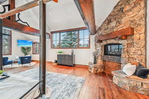Living area featuring hardwood / wood-style floors, beamed ceiling, high vaulted ceiling, and a fireplace