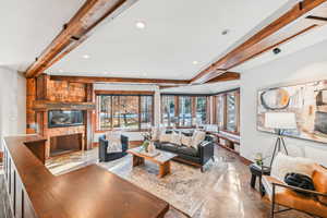 Living room featuring beam ceiling, a fireplace, plenty of natural light, recessed lighting, and finished concrete flooring