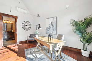 Office space with wood finished floors, a wall mounted AC, and high vaulted ceiling