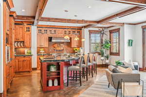 Kitchen featuring a kitchen bar, open shelves, pendant lighting, beam ceiling, and dark stone countertops