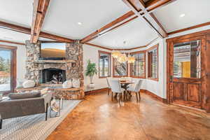 Dining space with concrete floors, a stone fireplace, a chandelier, beam ceiling, and recessed lighting