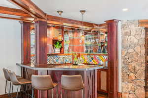 Community bar area featuring hanging light fixtures, reddish brown cabinets, and beamed ceiling