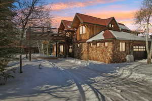 View of snowy exterior with stone siding and board and batten siding
