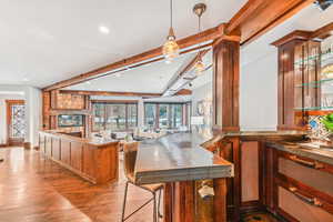 Kitchen featuring beam ceiling, light wood finished floors, pendant lighting, recessed lighting, and brown cabinetry