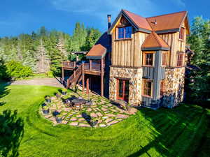 Back of house featuring a patio, board and batten siding, stone siding, and a wooden deck