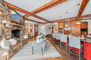 Living area featuring beamed ceiling, arched walkways, a fireplace, a chandelier, and dark wood finished floors