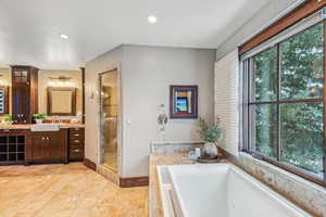 Bathroom with a bath, vanity, a stall shower, and recessed lighting