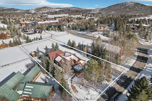 Snowy aerial view with a mountain view and property parcel outlined