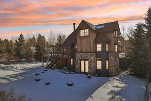 View of front facade with stairway, stone siding, and a wooden deck