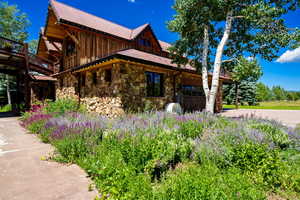 View of side of home with a metal roof, stone siding, board and batten siding, and a garage
