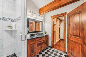 Bathroom featuring double vanity, a shower stall, and beam ceiling