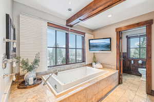 Bathroom with beam ceiling, a tub with jets, healthy amount of natural light, and recessed lighting