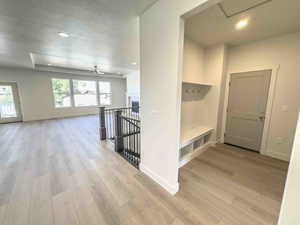 Hallway featuring an upstairs landing, a textured ceiling, recessed lighting, and light wood-type flooring