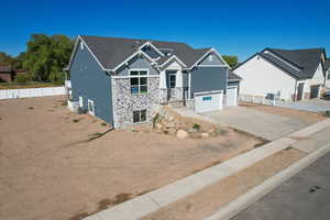 Craftsman house featuring board and batten siding, stone siding, driveway, and roof with shingles
