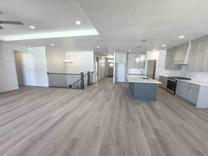 Kitchen featuring a chandelier, gray cabinetry, open floor plan, stainless steel range with gas cooktop, and recessed lighting