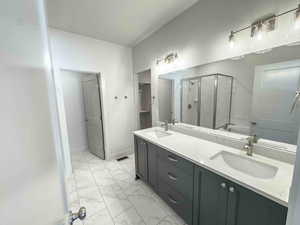 Bathroom with a shower stall, light marble finish flooring, double vanity, a spacious closet, and a garden tub