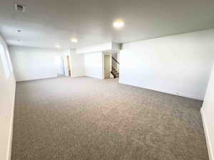 Carpeted empty room with stairway and recessed lighting
