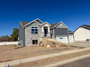 Craftsman house featuring stone siding, driveway, and board and batten siding