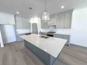 Kitchen featuring gray cabinetry, tasteful backsplash, a kitchen island with sink, a textured ceiling, and recessed lighting