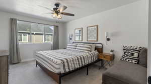 Carpeted bedroom featuring a ceiling fan and a textured ceiling