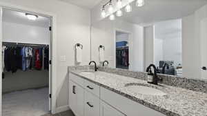 Master Bathroom featuring double vanity, a walk in closet, and light colored carpet