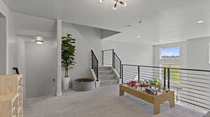 Corridor featuring light carpet, an upstairs landing, and a textured ceiling