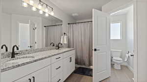 Master Bathroom featuring dark tile patterned flooring, double vanity, and shower / bathtub combination with curtain