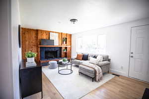 Living area featuring a fireplace with raised hearth, wood finished floors, and wood walls