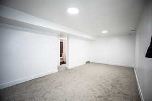 Finished basement with light colored carpet and recessed lighting