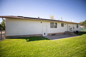 Rear view of property featuring a yard, a patio area, and solar panels