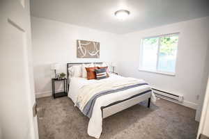 Bedroom featuring a baseboard heating unit and carpet floors