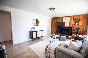 Living area with wood finished floors, a fireplace with raised hearth, and wood walls