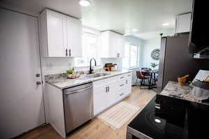 Kitchen with light wood-style floors, dishwasher, range with electric cooktop, white cabinetry, and recessed lighting