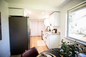 Kitchen with light stone counters, appliances with stainless steel finishes, white cabinetry, healthy amount of natural light, and recessed lighting